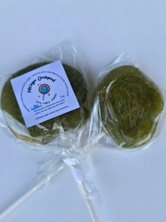 Two blue green spirulina lollipops in clear packaging with a label on a white background says contains honey