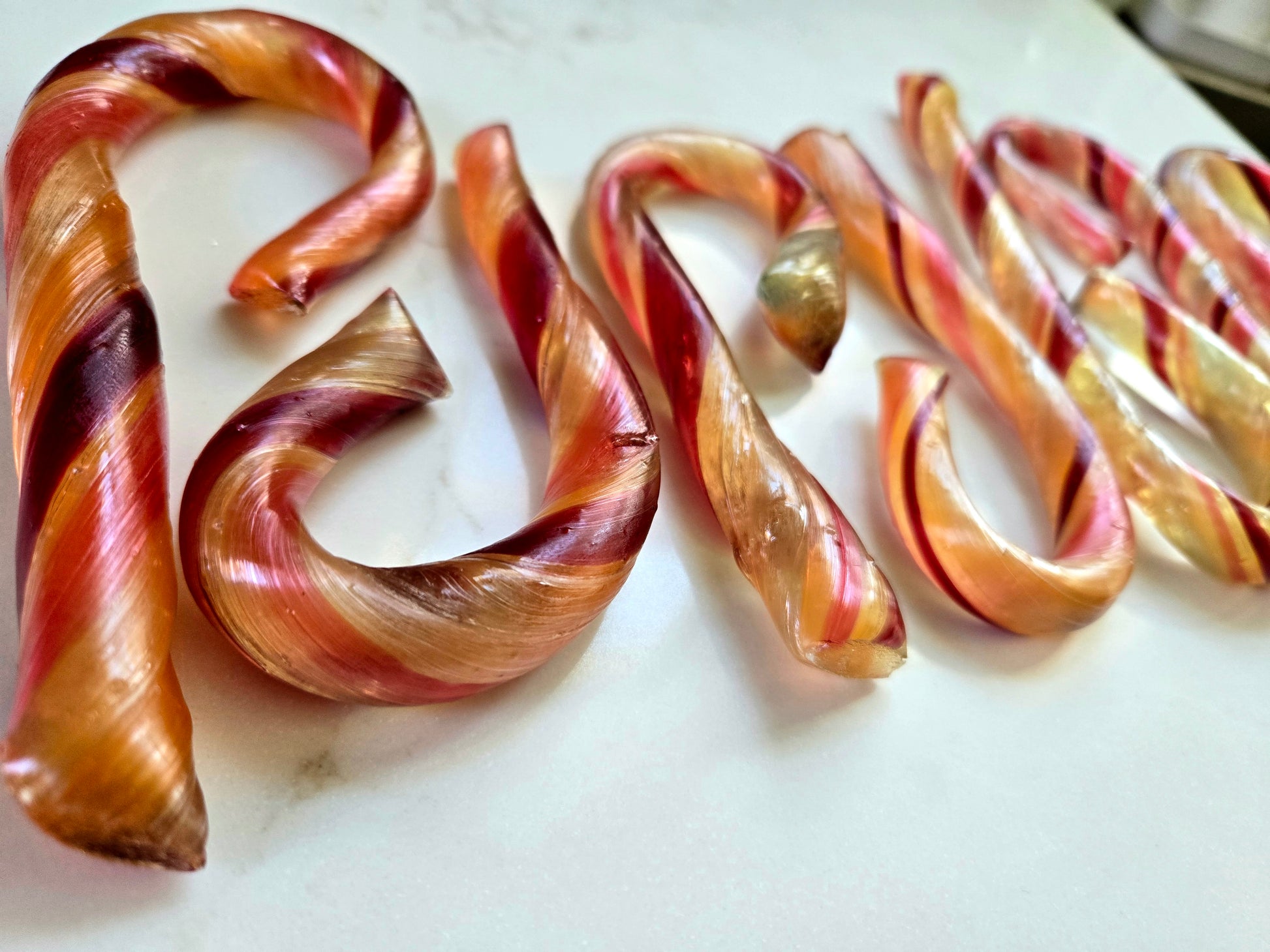 Colorful rainbow giant candy canes on a white marble surface