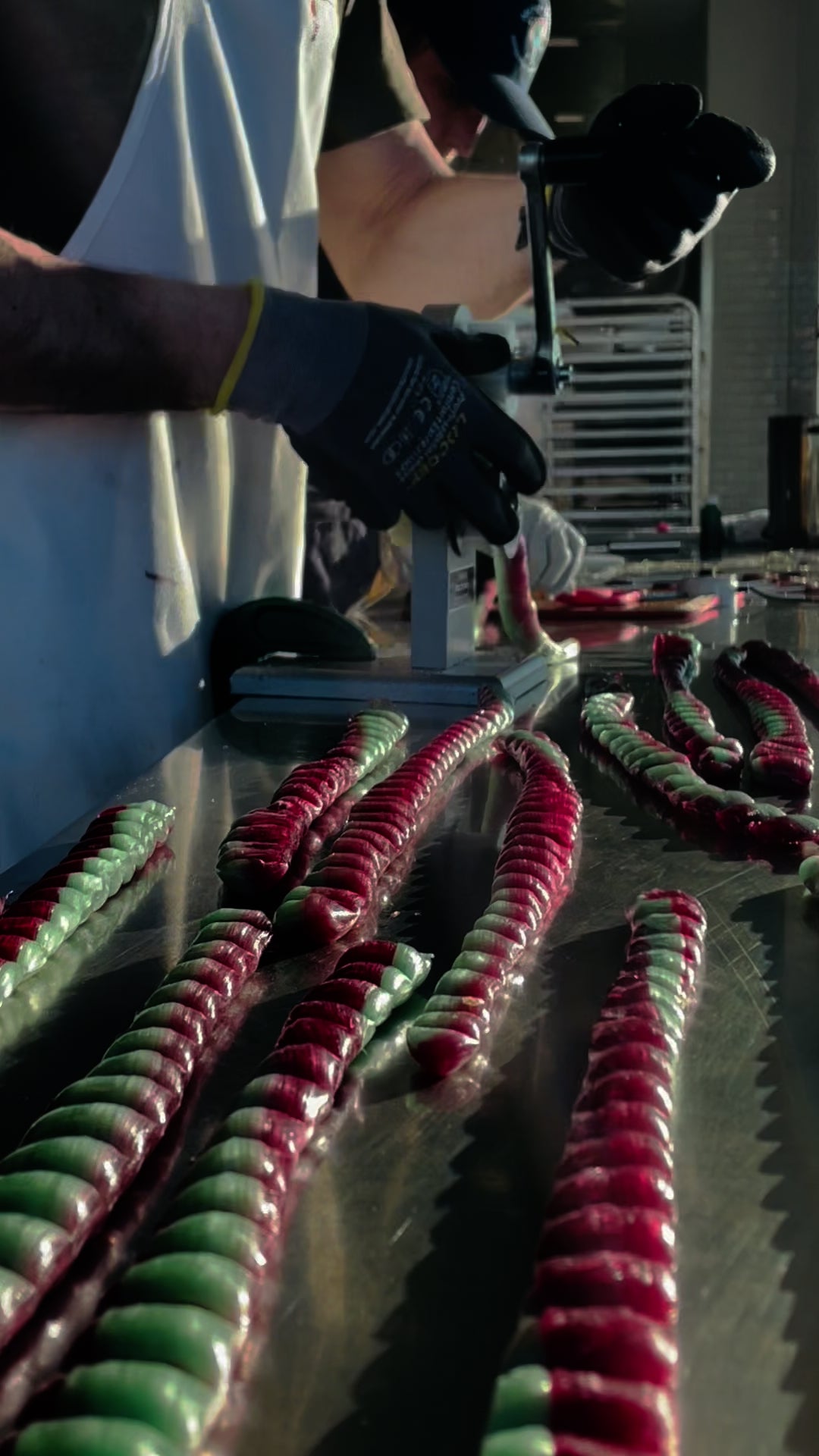 Load video: We are pulling red and green colored candy through a machine that makes it into a pillow shape before it hardens.