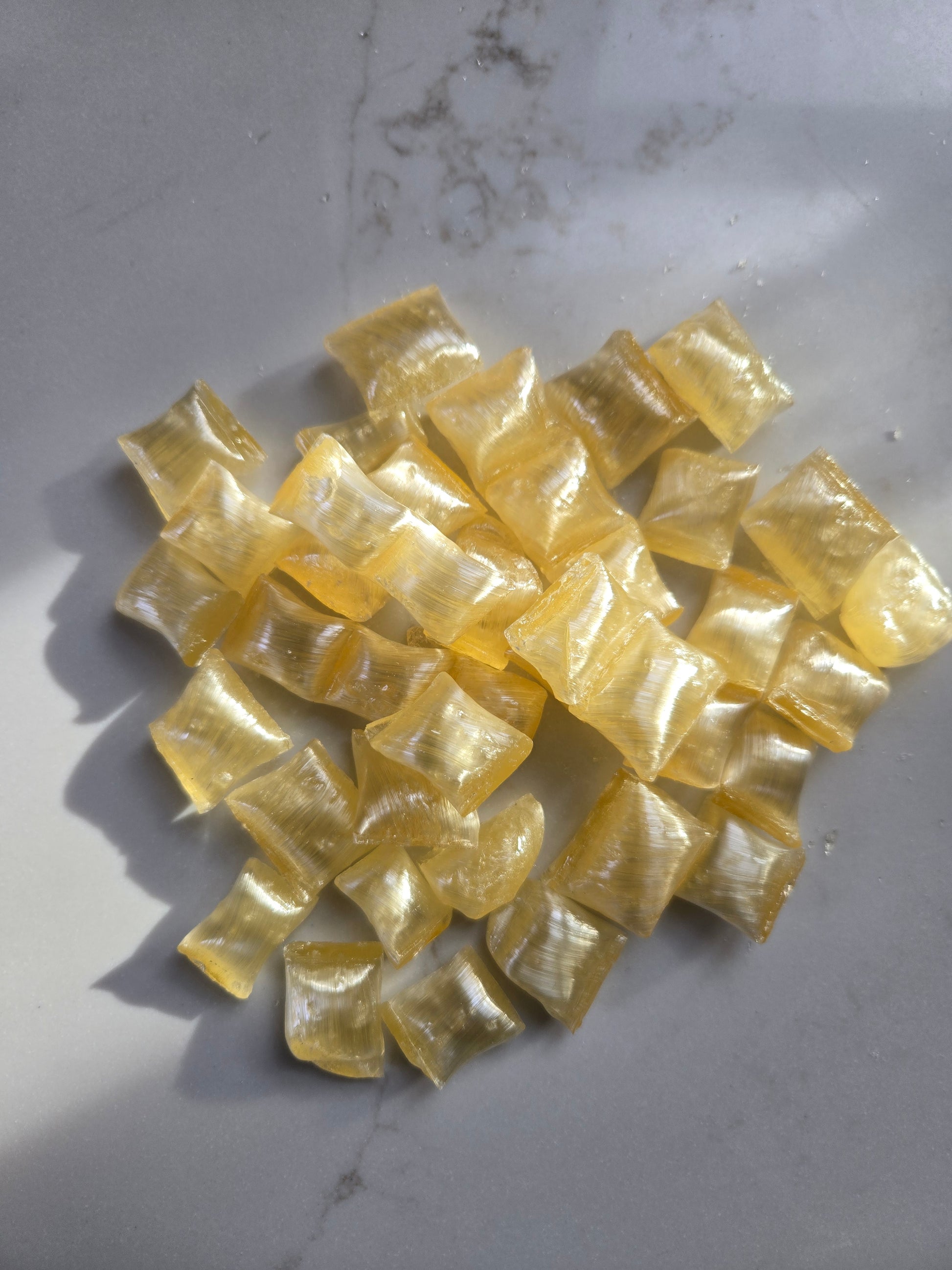 Golden Yellow square pillow salty caramel candies on a gray marble surface